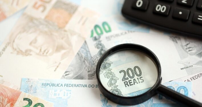 Notas de real e calculadora. Foto que ilustra post sobre arrecadação federal. Reprodução: Mehaniq41/Envato.