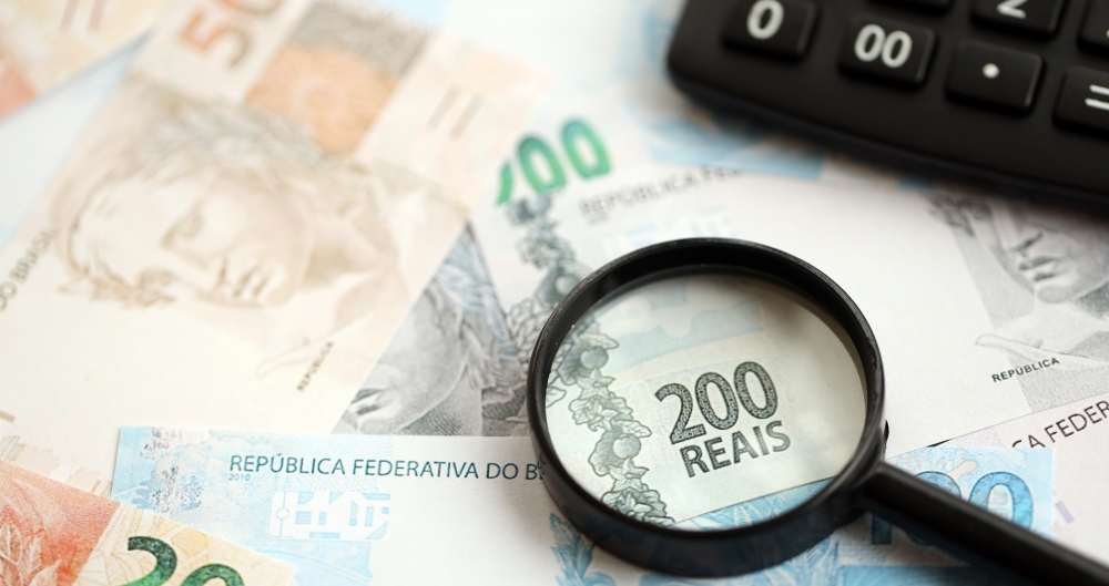 Notas de real e calculadora. Foto que ilustra post sobre arrecadação federal. Reprodução: Mehaniq41/Envato.
