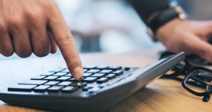 Pessoa fazendo contas em uma calculadora. Foto que ilustra post sobre extrafiscalidade. Reprodução: GoldenDayz/Envato.