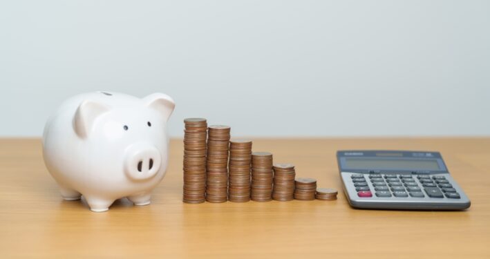Porquinho, moedas e calculadora. Foto que ilustra post sobre federalismo fiscal. Reprodução: JoPanwatD/Envato.