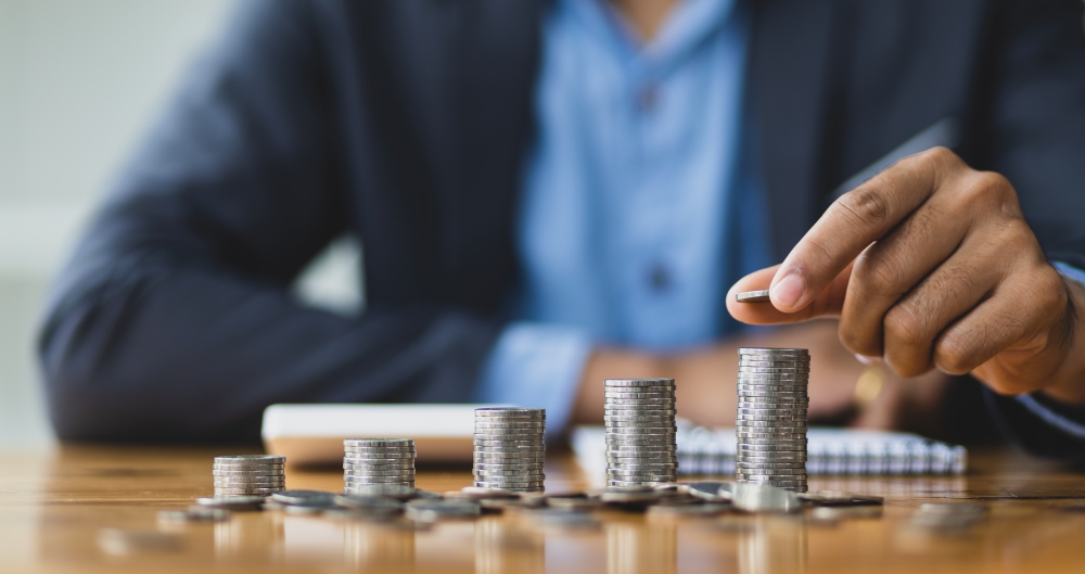 Pessoa contando moedas, em foto que ilustra post sobre compensação financeira. Reprodução: wasant1/Envato.