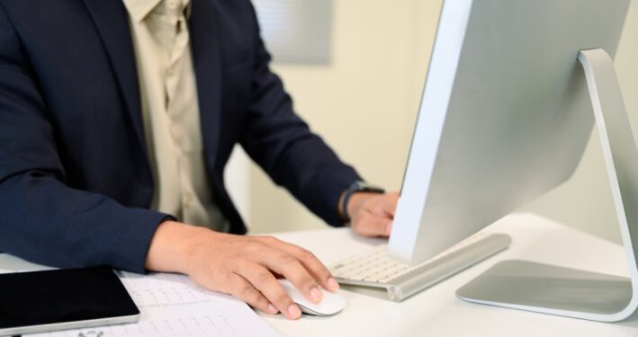 Homem usando computador, em foto que ilustra post sobre Domicílio Tributário Eletrônico (DTE). Reprodução: prathanchorruangsak/Envato.