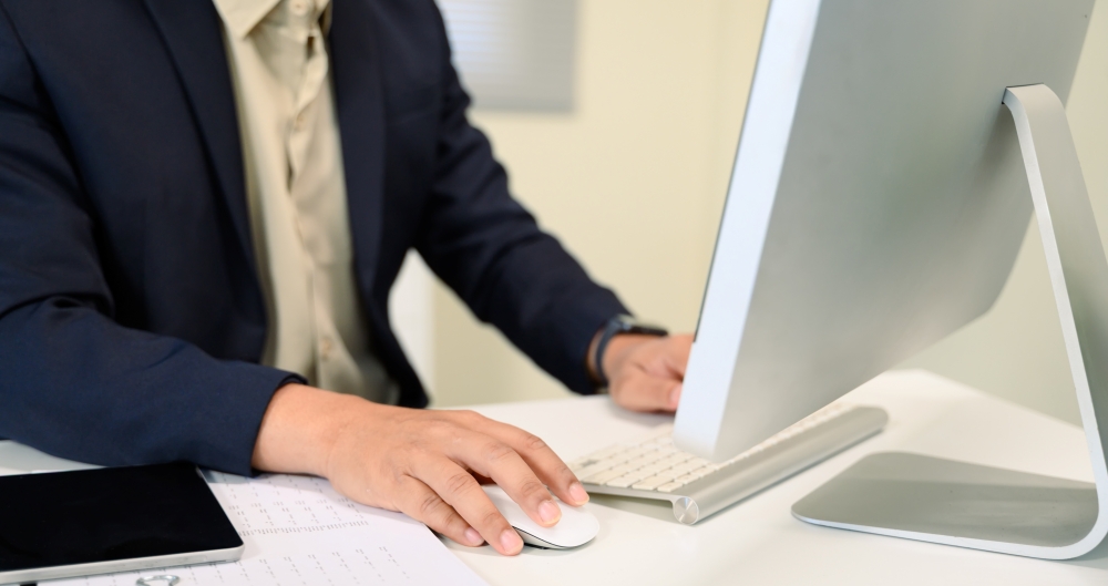 Homem usando computador, em foto que ilustra post sobre Domicílio Tributário Eletrônico (DTE). Reprodução: prathanchorruangsak/Envato.